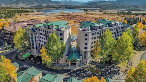 A multi-story hotel with a central courtyard and a view of a lake and mountains. - Stunning Vista at Alpine Buzz (Frisco)