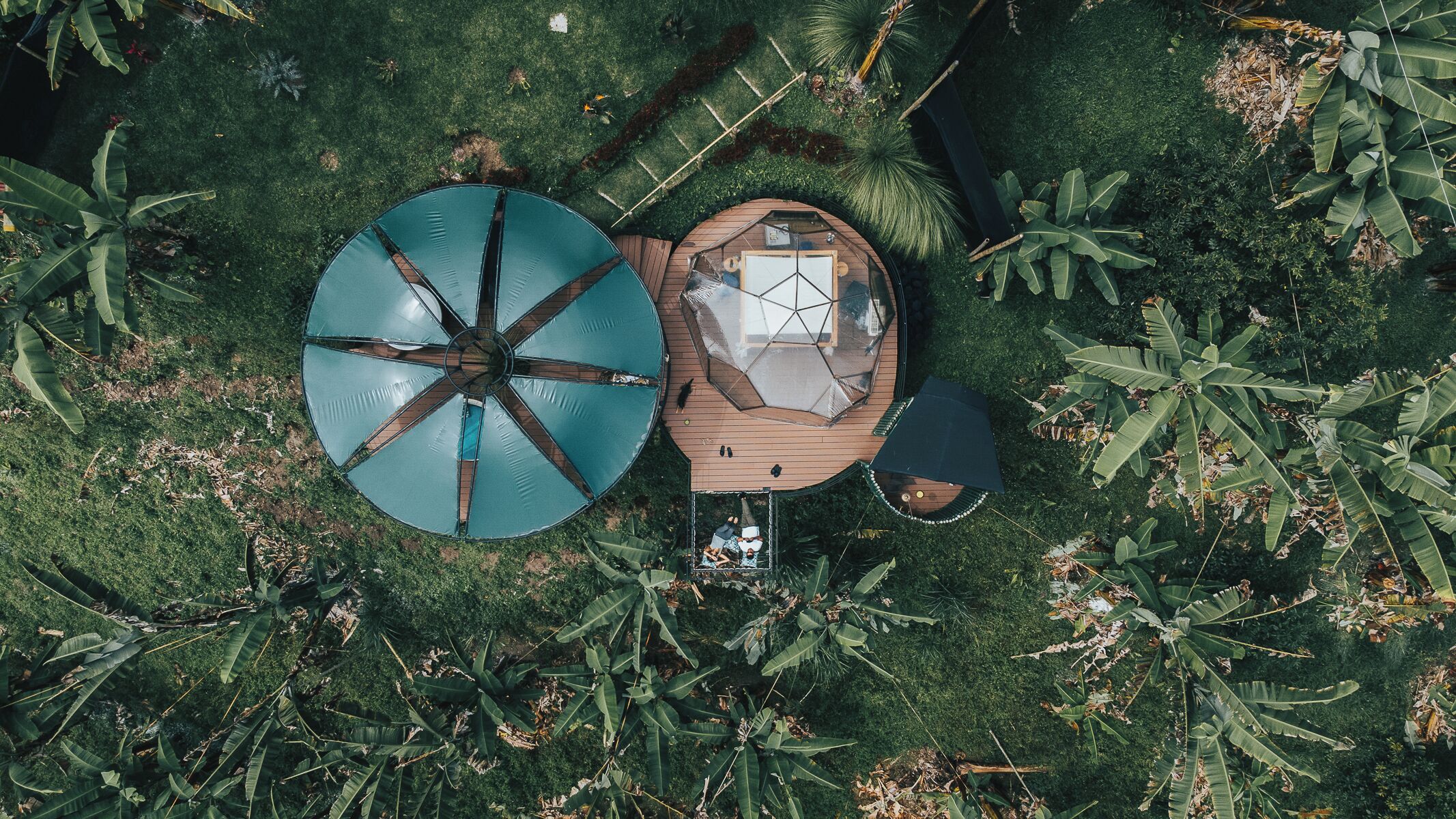 A circular outdoor seating area with a central table and chairs, surrounded by lush greenery.