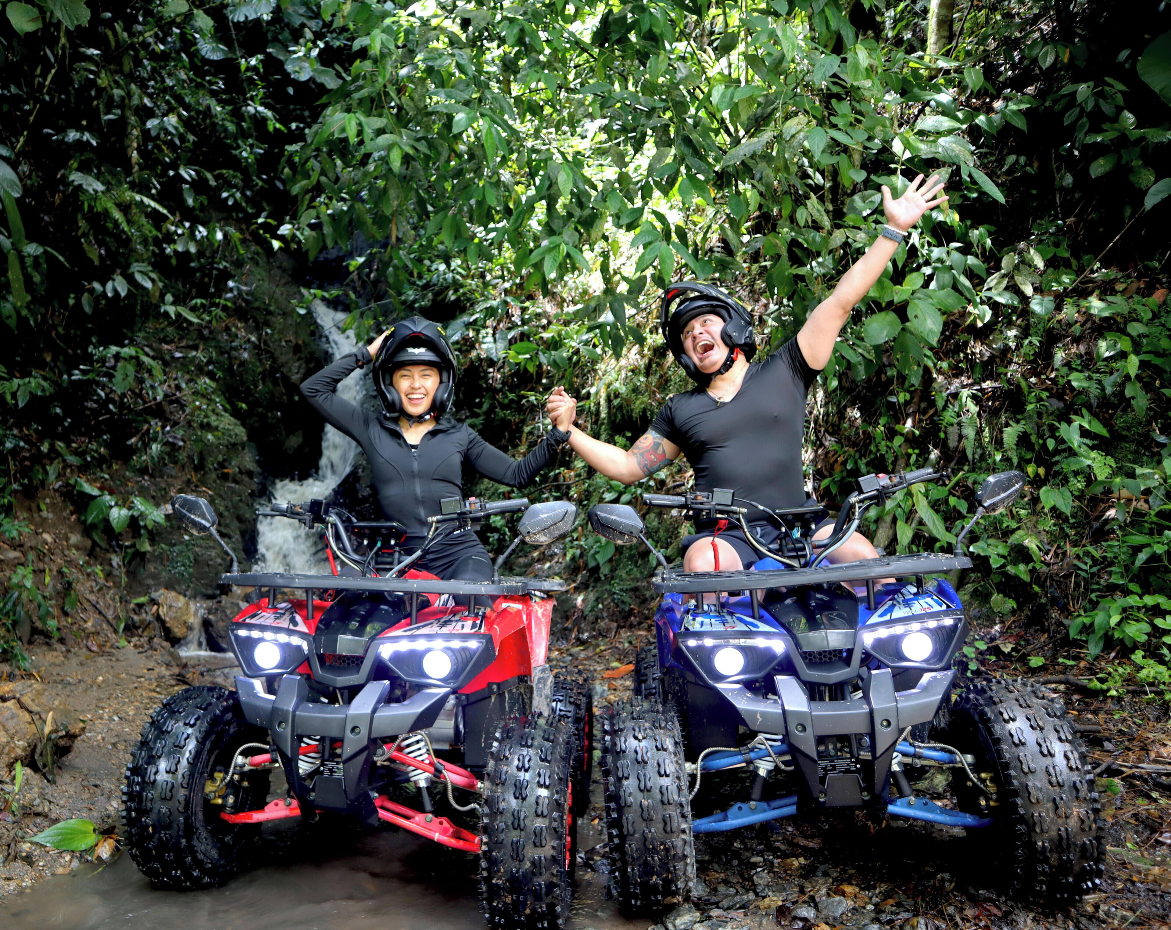 Two people on ATVs in a forested area.