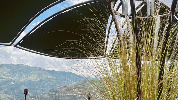 A wicker chair on a terrace with a view of mountains. - Chamí Glamping (Manizales)