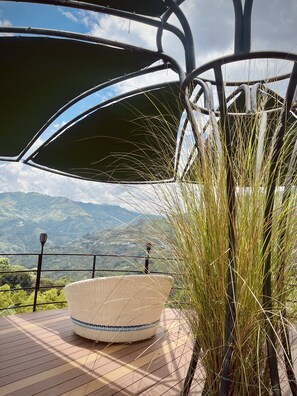 A wicker chair on a terrace with a view of mountains. - Chamí Glamping (Manizales)