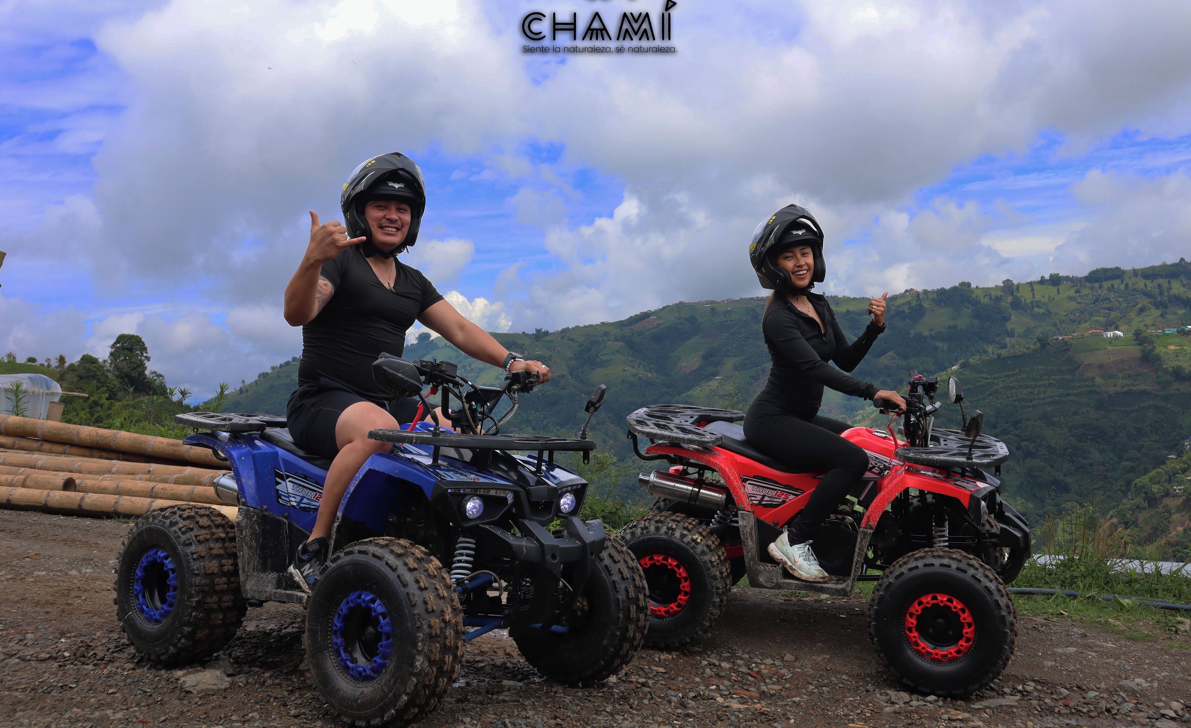 Twee personen op quad bikes, met het logo 'CHAMI' en een mooi uitzicht op glooiende heuvels.