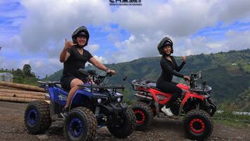 Twee personen op quad bikes, met het logo 'CHAMI' en een mooi uitzicht op glooiende heuvels.