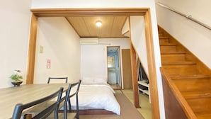 Una habitación pequeña con una mesa de madera, una cama y una escalera.