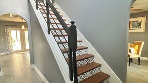 Eine Treppe mit schwarzer Handläufe und gemusterten Stufen, die zu einer oberen Etage führt.