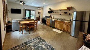 Een moderne keuken met houten kastjes, een roestvrijstalen koelkast en een eethoek met een tafel en stoelen.