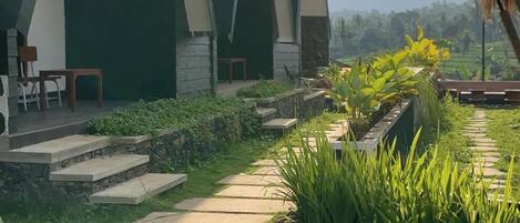 A modern building with a unique triangular roof design, surrounded by a well-maintained garden with a stone pathway.