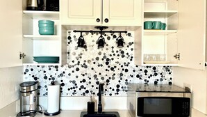 A kitchen with white cabinets, a coffee maker, a microwave, and a sink.