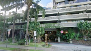 A multi-story building with a speed limit sign of 25 mph, surrounded by palm trees and greenery. - Rare 10mins 2Qn Beds Waikiki 4person (Honolulu)