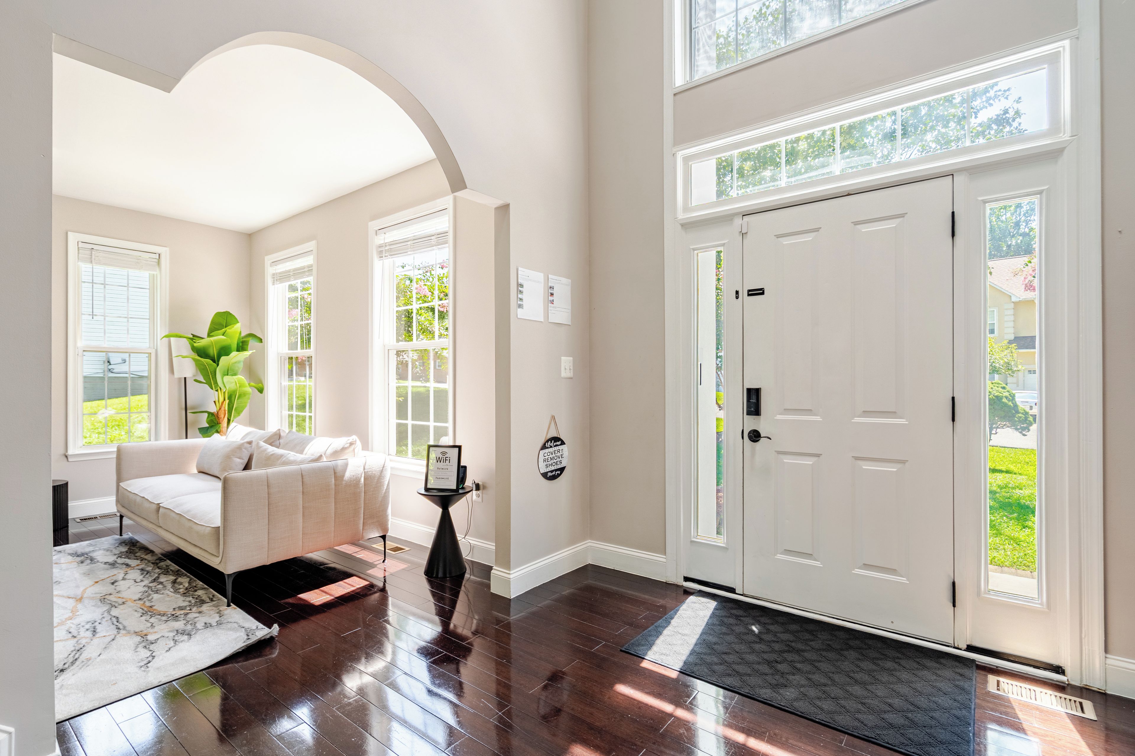 A spacious living room with a white sofa, a coffee table, and a large window.