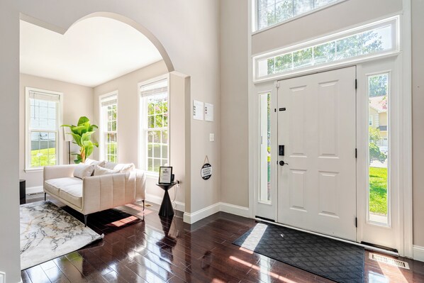 A spacious living room with a white sofa, a coffee table, and a large window.