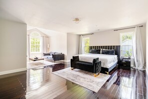 A spacious bedroom with a large bed, a sofa, and a dining table.