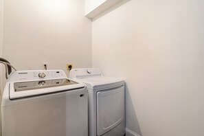 Zona de bugaderia amb una rentadora intel·ligent Samsung Smartcore i un assecador blanc.