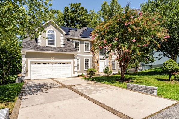 A two-story house with a garage, a stone facade, and a well-maintained lawn.