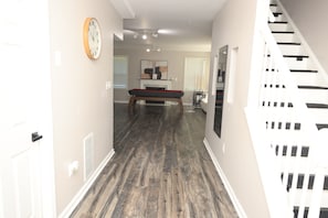 A hallway with a billiards table, a staircase, and a door.