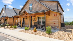 A log cabin-style building with a covered porch, outdoor seating, and a view of the surrounding landscape.