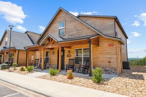 A log cabin-style building with a covered porch, outdoor seating, and a view of the surrounding landscape.