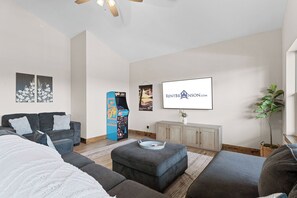 Una sala de estar moderna con un conjunto de sofá, un televisor de pantalla plana y un tablero decorativo.