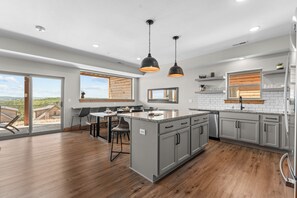 Una cocina moderna con armarios grises, una isla central e iluminación colgante.
