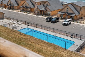 Un hotel con piscina, sillones de descanso para huéspedes y zona de estacionamiento.