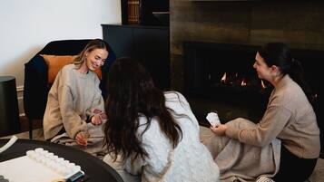A group of people sitting on the floor in a cozy room with a fireplace.