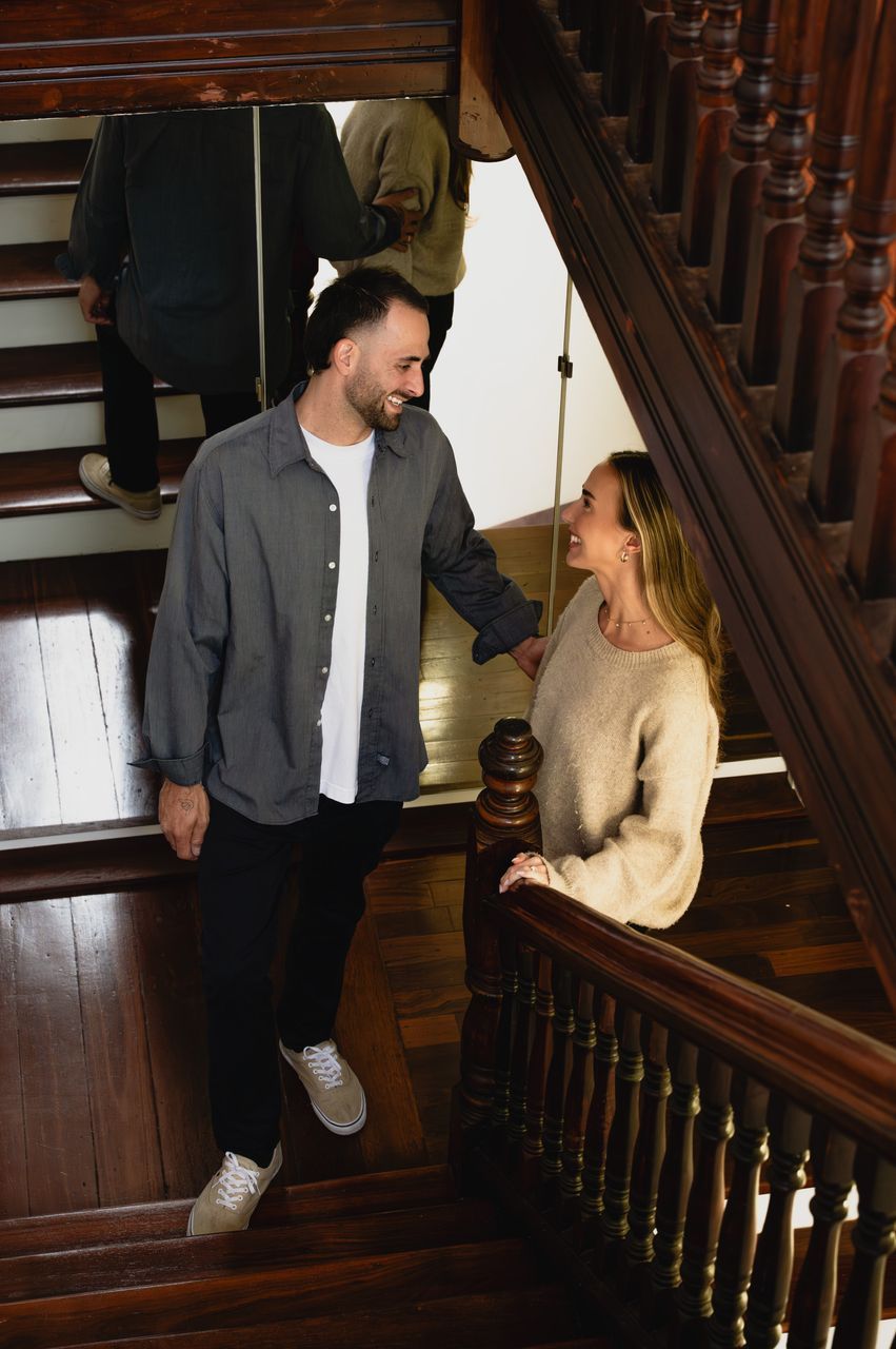A wooden staircase with a handrail and a person standing on the steps.
