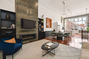A modern living room with a fireplace, a television, and a dining area with a view of the city.