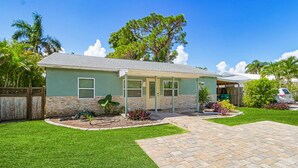 A single-story house with a covered patio, a stone pathway, and a well-maintained lawn.