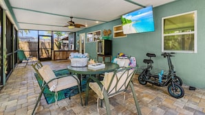 A covered patio with a round table, chairs, and a bicycle.