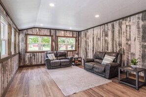 A room with two leather sofas, a rug, a small table with a plant, and wooden walls with windows. - Large Group Retreat w/ Indoor Pickleball (Dalton)