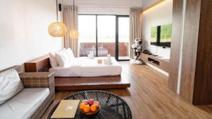 Et moderne hotelværelse med en stor seng, en sofa, et spisebord med frugt og et TV ophængt på væggen.