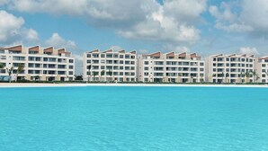 A beachfront hotel with multiple buildings, a clear blue sky, and calm sea.