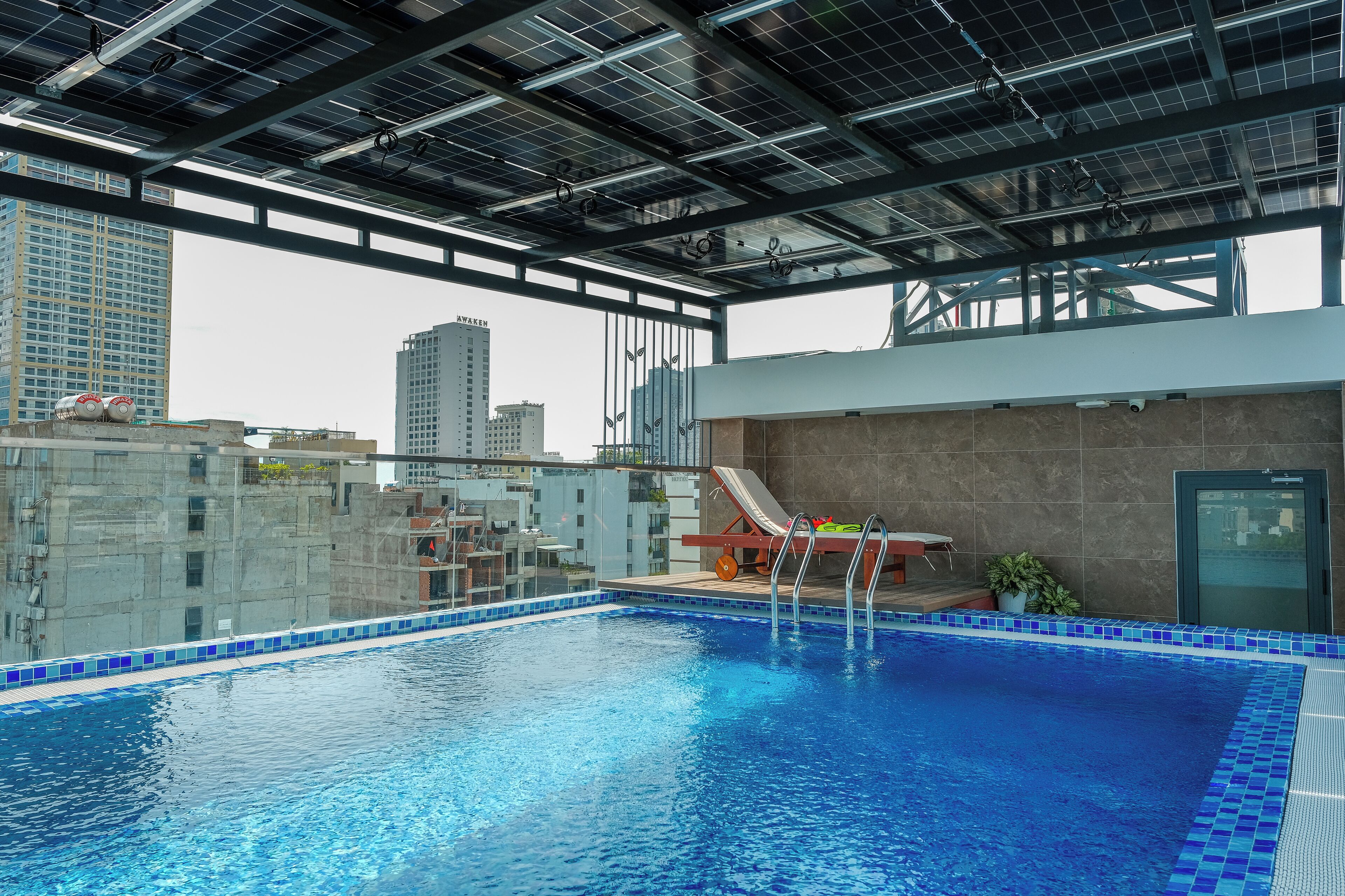 Una piscina interior con vista a un paisaje urbano, una silla de descanso y una puerta.