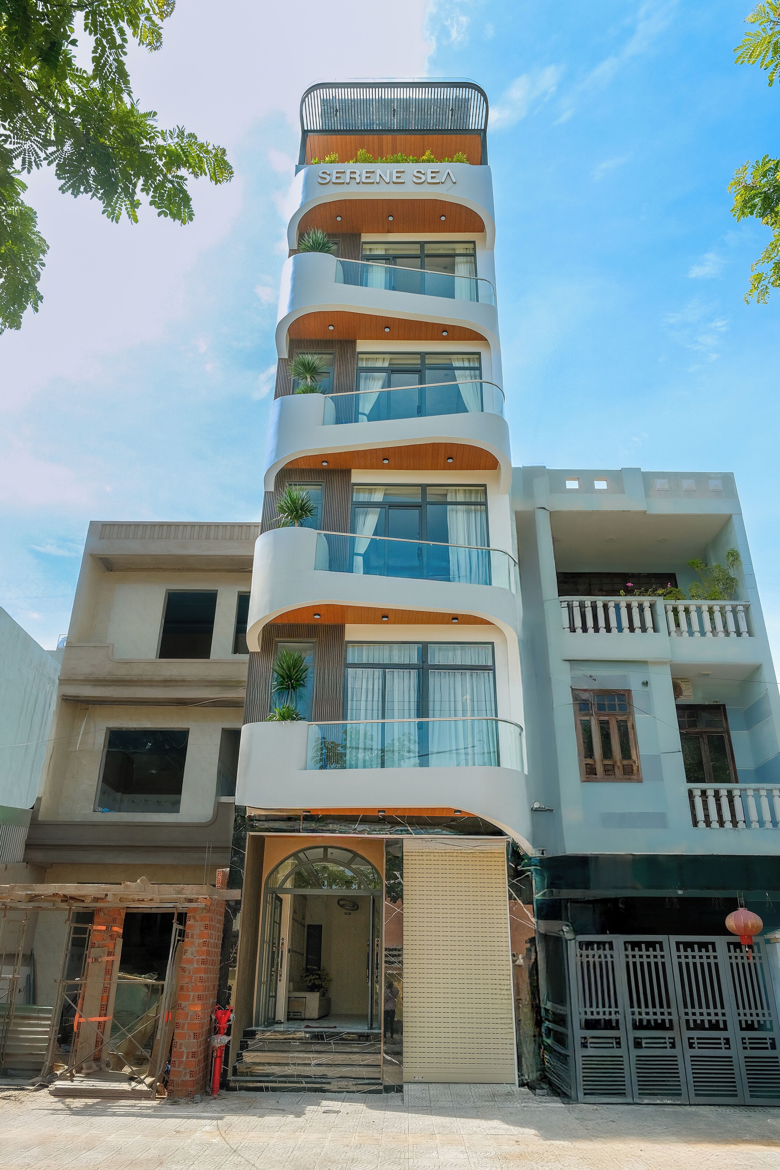A multi-story building with balconies, a central entrance, and a sign reading 'SERENE SEA'.