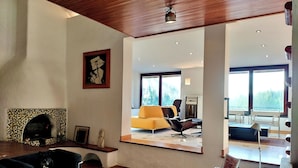 Un salon moderne avec une cheminée, un canapé, une table basse et une grande fenêtre donnant sur l’extérieur.