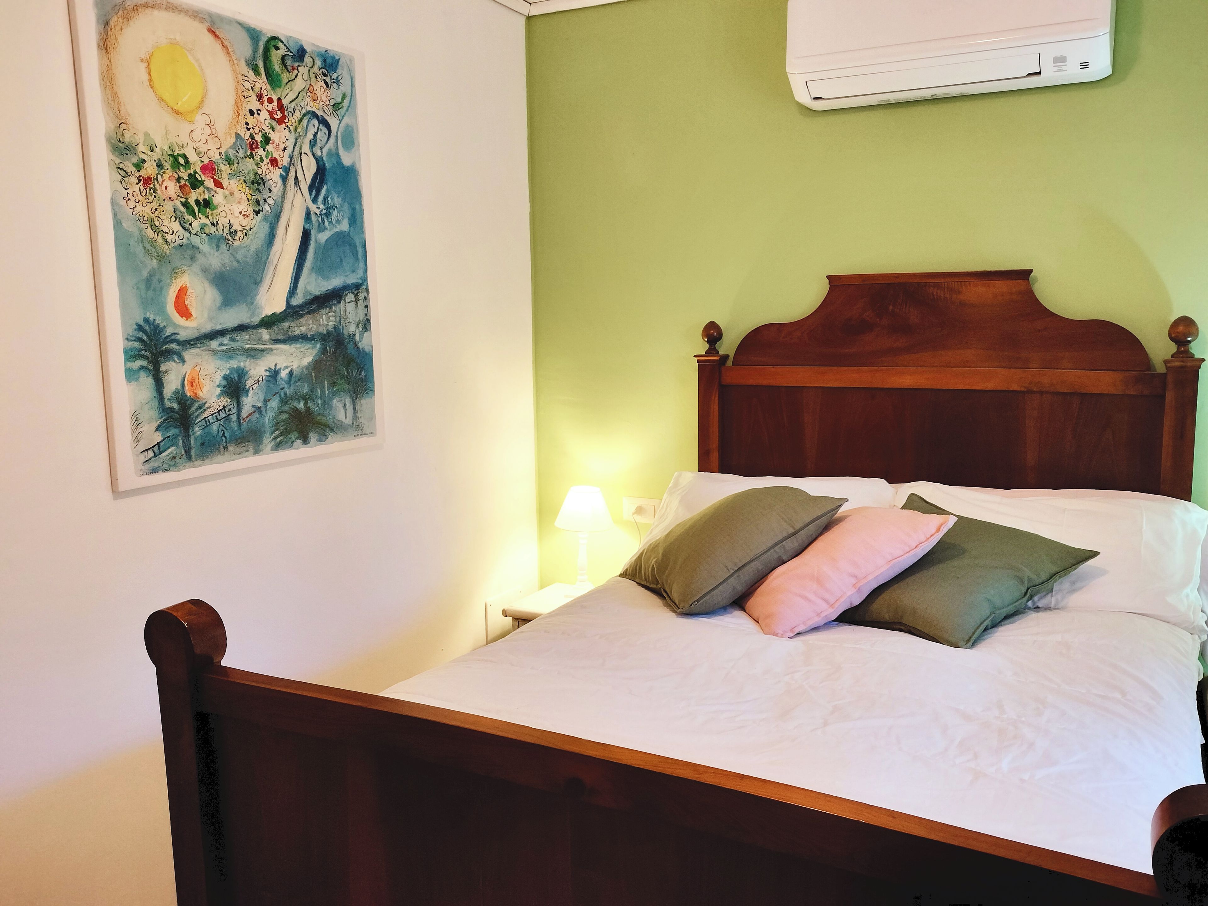 A bed with a wooden headboard, white bedding, and multiple pillows.