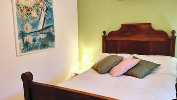 A bed with a wooden headboard, white bedding, and multiple pillows.