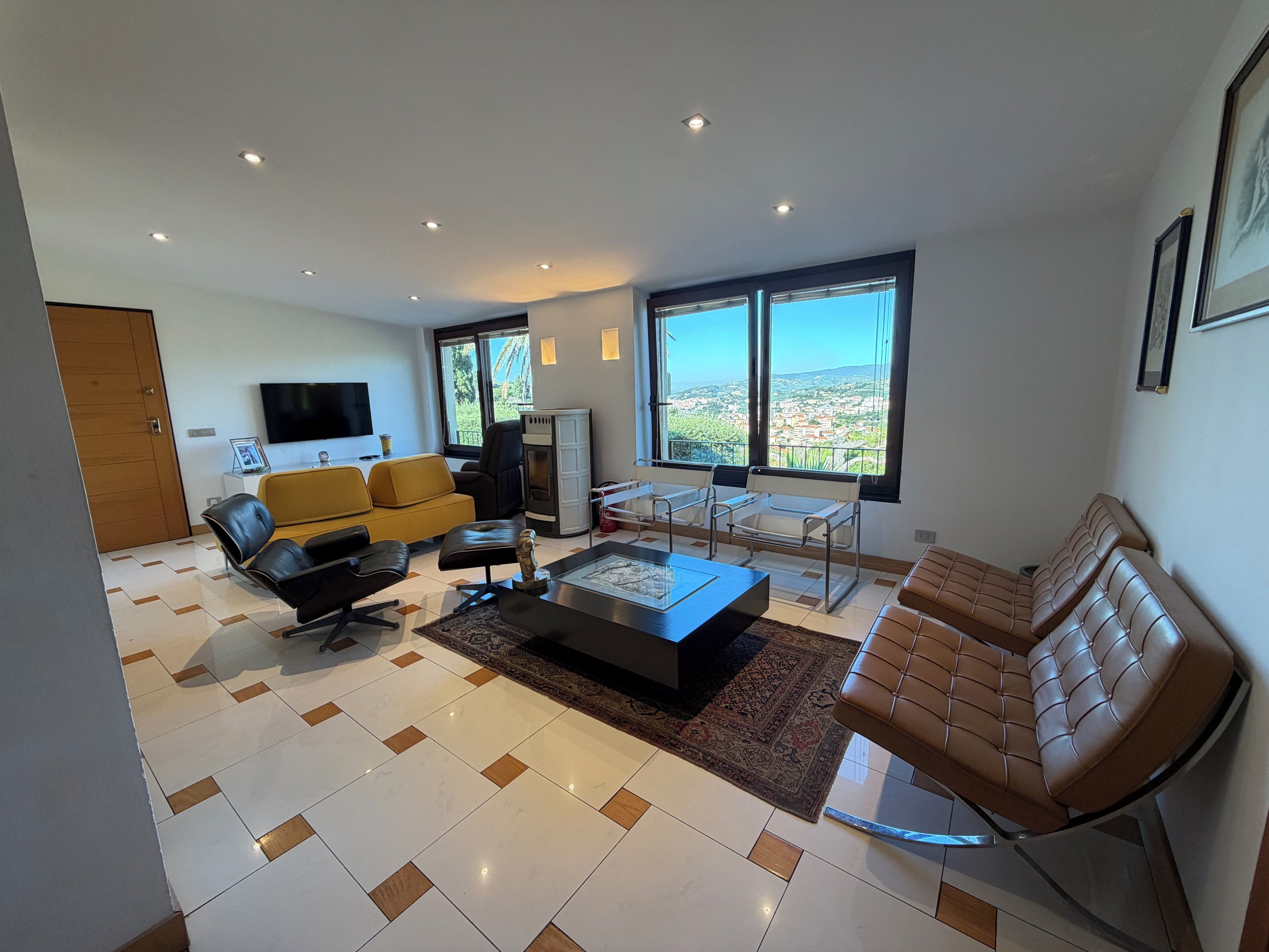 A modern living room with a sofa, armchairs, a coffee table, and a television.