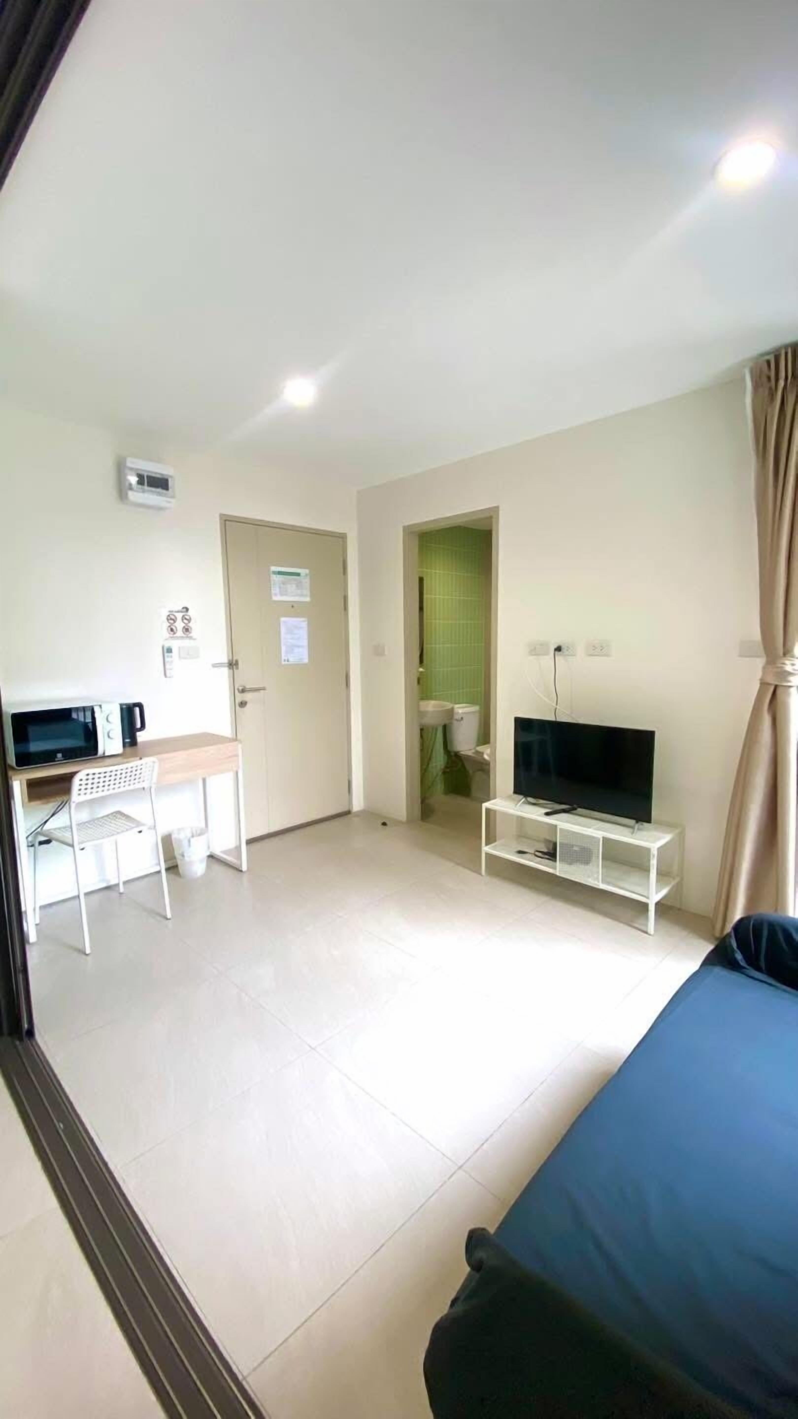 A room with a bed, a TV, a desk with a chair, and a microwave.