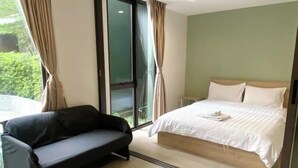 Une chambre moderne avec un grand lit, un canapé et une porte-fenêtre coulissante donnant sur un balcon.