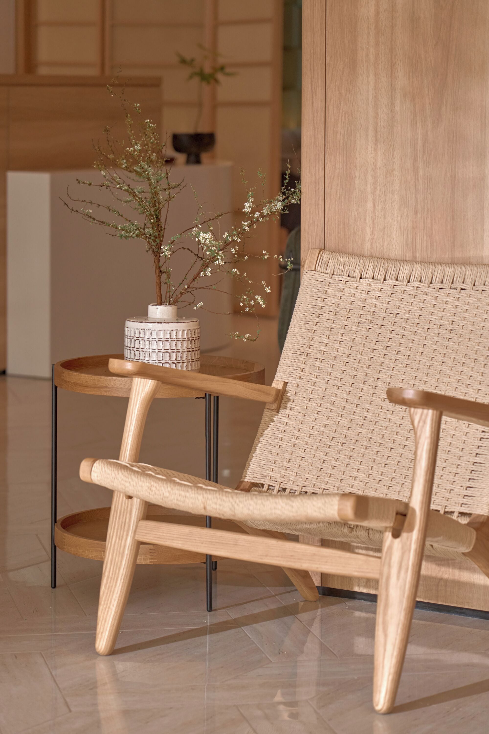 A wooden chair with a woven backrest and a small table with a vase of flowers.