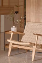 A wooden chair with a woven backrest and a small table with a vase of flowers.