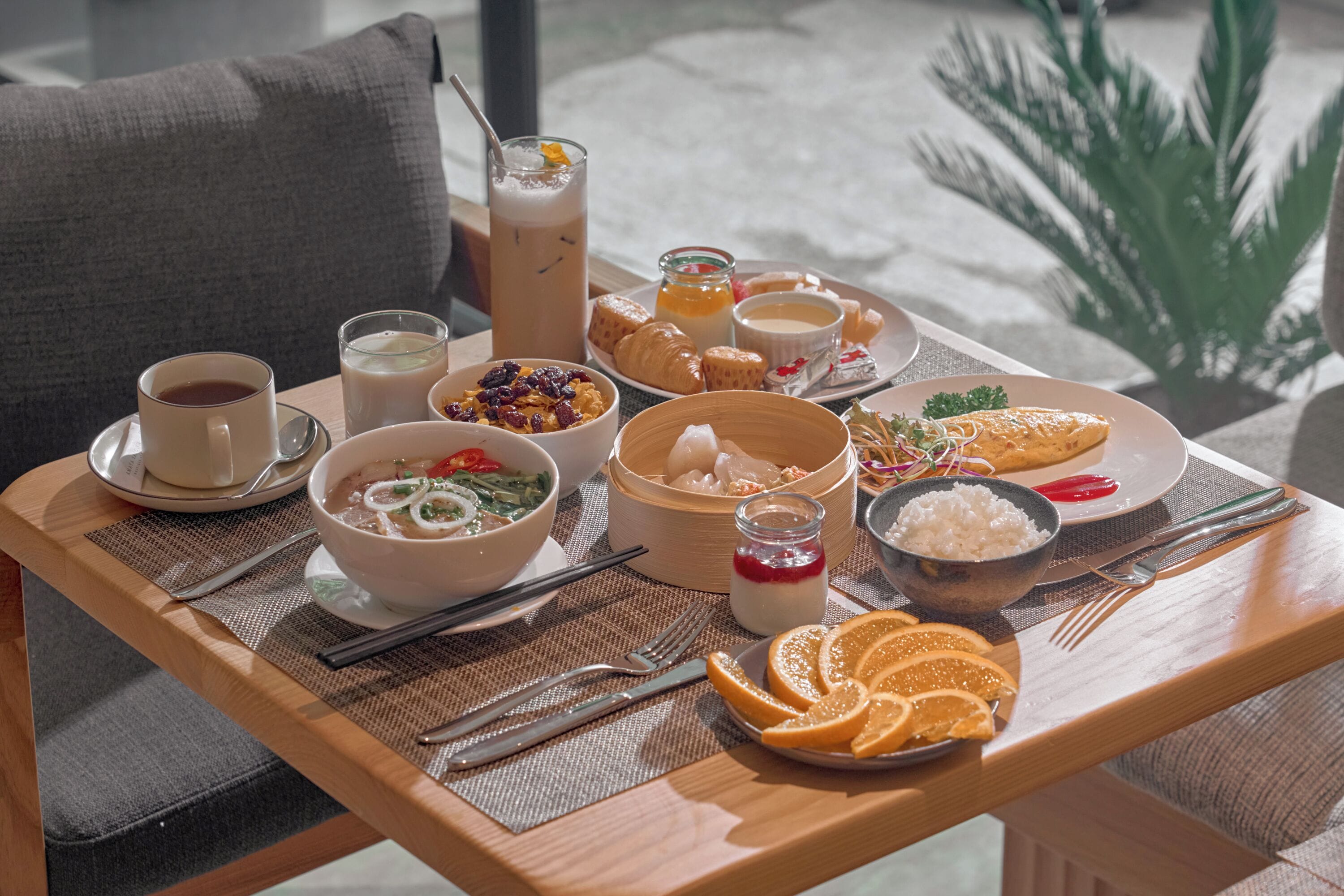 A breakfast tray with various foods and drinks, including a bowl of soup, a plate of pastries, and a glass of milk.
