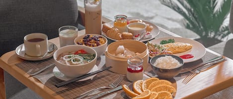 Un plateau de petit-déjeuner contenant divers aliments et boissons, notamment un bol de soupe, une assiette de viennoiseries et un verre de lait.