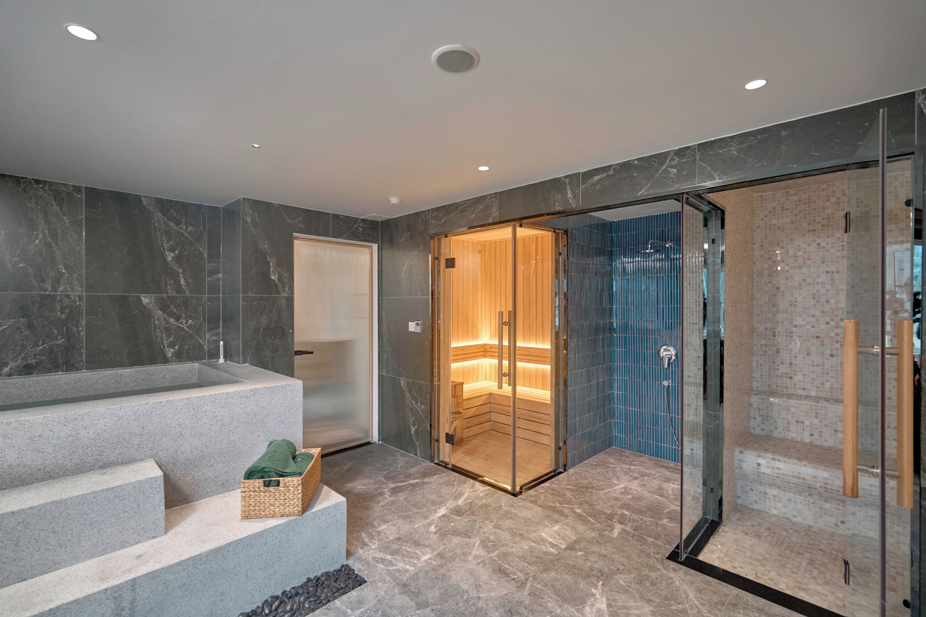 A modern bathroom with a large bathtub, a glass-enclosed sauna, and a shower area.