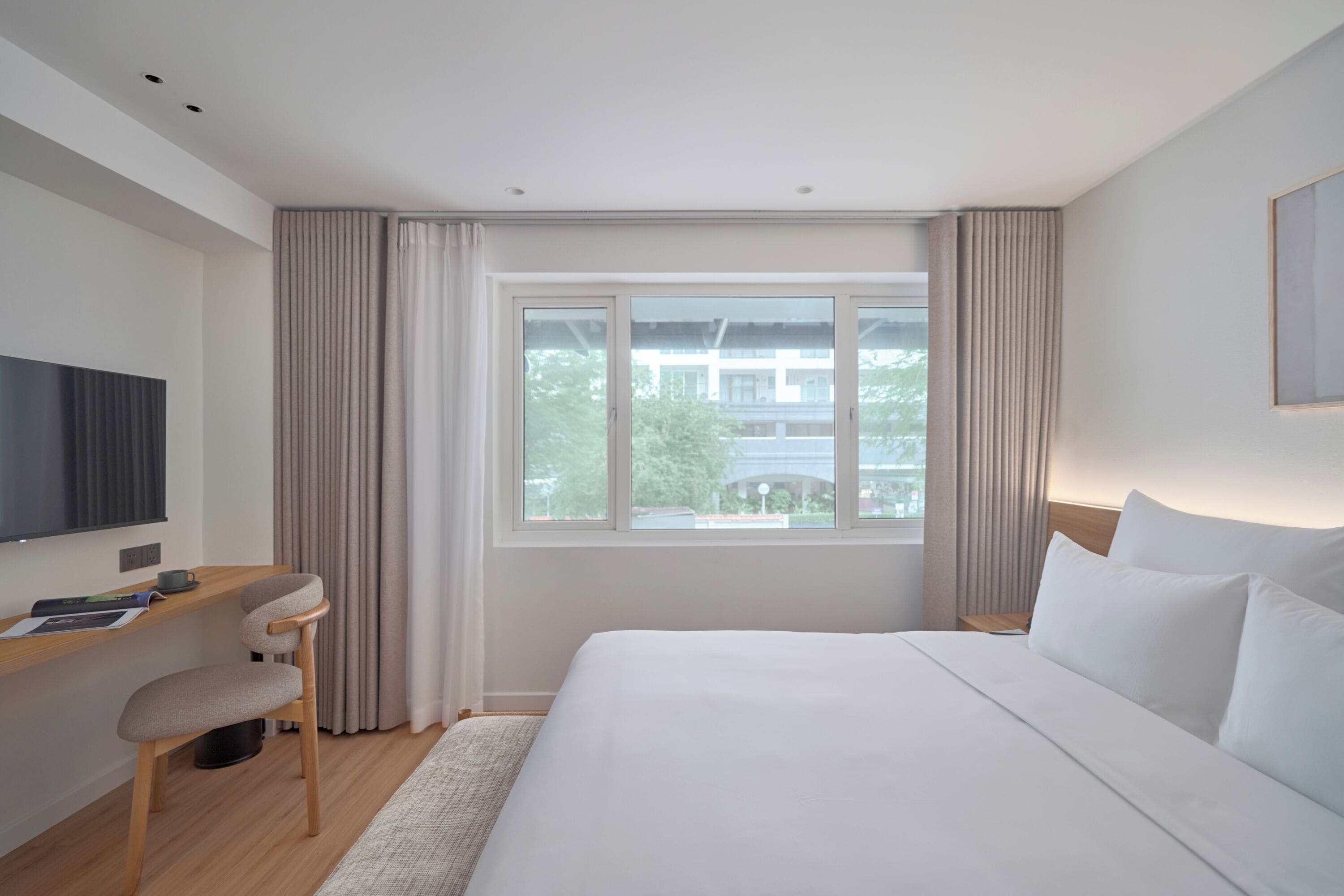 Una habitació d'hotel moderna amb un llit gran, un escriptori i una televisió.
