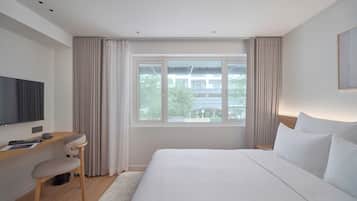 Une chambre d’hôtel moderne avec un grand lit, un bureau et une télévision.