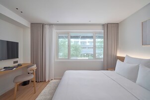 Une chambre d’hôtel moderne avec un grand lit, un bureau et une télévision.