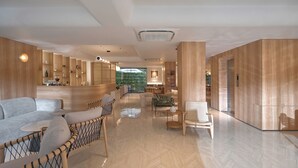 A spacious lobby with a herringbone floor, wooden paneling, and a seating area with sofas and chairs. - Amaya Saigon Boutique Hotel (Ho Chi Minh City)