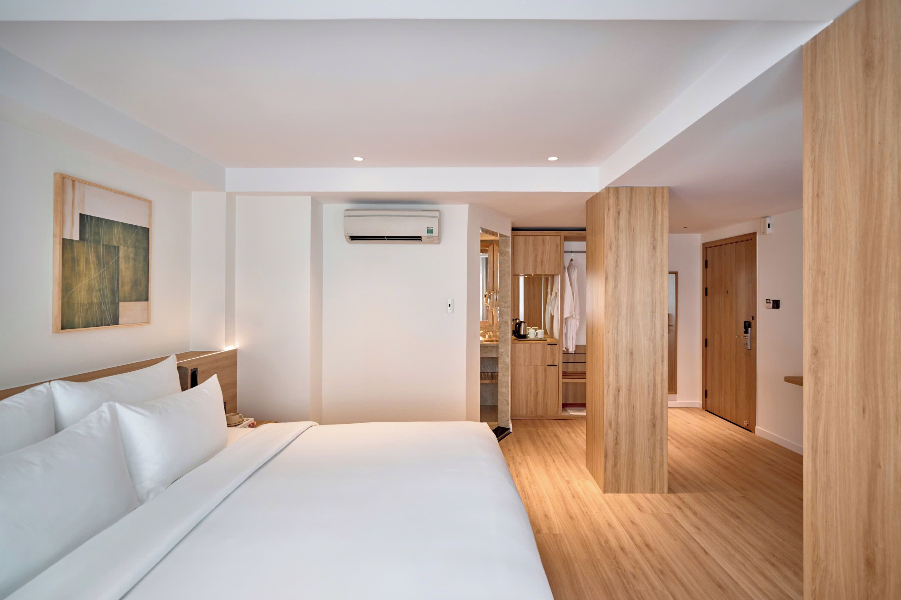 A modern hotel room with a large bed, a wardrobe, and a bathroom visible through an open door.